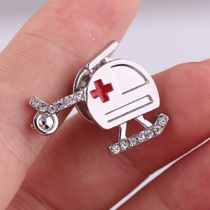 Macro view of silver medical helicopter brooch with red cross and inlaid rhinestones