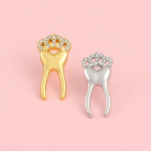 Close-up of crown-topped tooth brooches in gold and silver with sparkling rhinestones