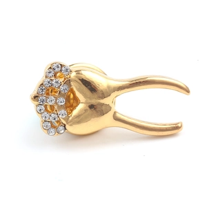 Detailed view of golden tooth brooch featuring a sparkling crown with white rhinestones