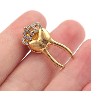 Detailed macro view of a gold-plated tooth brooch with a crown and sparkling rhinestones