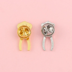 Golden and silver metal pin backings with butterfly clutch on pink background