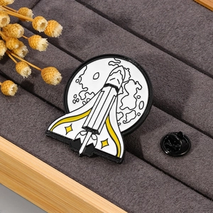 Space rocket enamel pin with star detail on dark velvet jewelry display tray