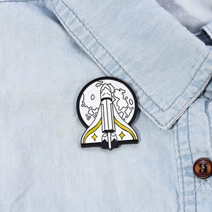 Space shuttle enamel pin on a denim jacket featuring a rocket and moon design