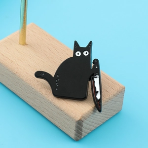 Funny black cat enamel pin with knife on wood block against a bright blue background
