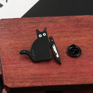 Macro detail of cartoon black cat enamel pin with knife on red wooden background