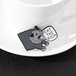 Cartoon opossum enamel pin featuring Eat The Rich text on a white ceramic plate