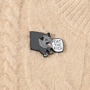 Detail of screaming opossum enamel pin with 'EAT THE RICH' text on a knit sweater