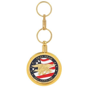 Detailed macro view of a gold metal Navy SEALs insignia keychain on a white background