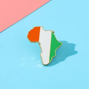 Detailed close-up of Ivory Coast flag map brooch with gold-plated finish on colorful background
