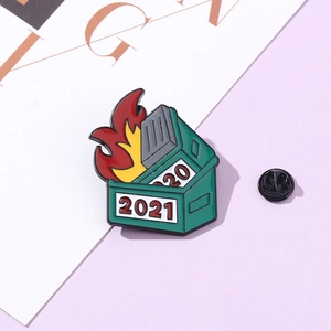 Detailed close-up of dumpster fire enamel pin with 2020 and 2021 date charms