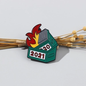 Detail view of green dumpster fire enamel pin with 2020 and 2021 digits on grey background