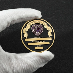 Detail of purple heart military merit medal coin held in gloved hand against black background