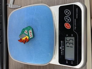 Dumpster fire enamel pin weight measurement of 13.5g on a digital kitchen scale