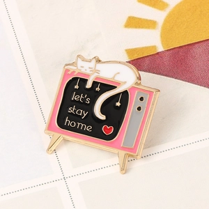Détail d'une broche chat TV rose en émail avec texte let's stay home et petit chat blanc