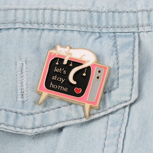 Détail d'un pin's émaillé de télévision rétro avec un chat et texte sur du tissu denim