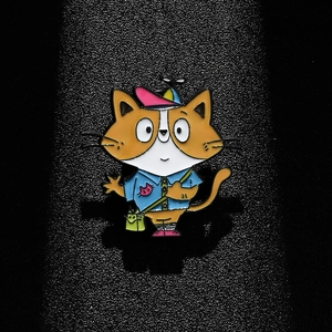 Cartoon orange cat enamel pin with propeller hat and green crossbody bag on dark base