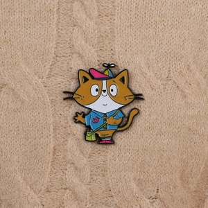 Detailed view of cartoon cat enamel pin with propeller hat on a beige knit sweater
