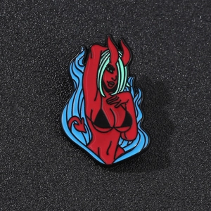Detail of red cartoon devil enamel pin with blue fire and heart tail on metal badge