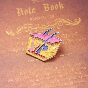 Detail of medical anatomy enamel pin showing skin tissue layers on leather notebook