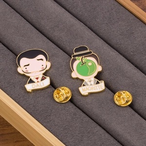 Detailed view of Dali and Magritte enamel pins displayed in a gray velvet jewelry tray
