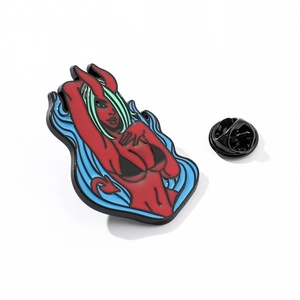 Detail of red cartoon succubus enamel pin with green hair and blue fire on white backdrop