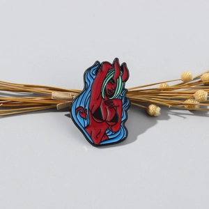 Close-up of red succubus enamel pin with black metal outlines and gothic design