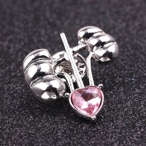 Macro shot of silver kidney brooch featuring a pink heart gem on a black texture