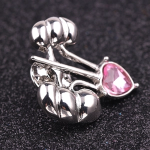 Macro detail of pumpkin brooch in silver with a pink heart crystal on black background