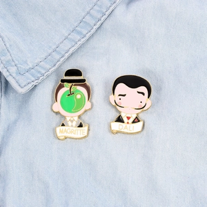 Cartoon Dali and Magritte enamel pin set with artistic metal badges on blue denim background