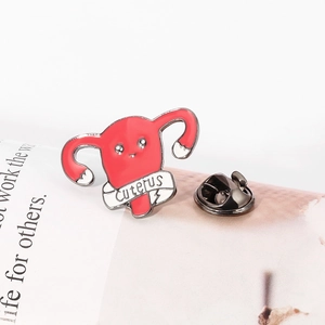 Détail du pin's émaillé utérus rose avec bannière Cuterus et fermoir papillon