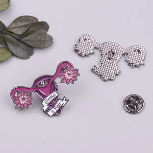 Detail of uterus enamel pin featuring pink flowers and Grow a Pair text engraving