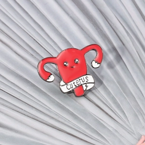Détail d'un pin's en émail utérus rouge avec bannière décorative et texte Cuterus
