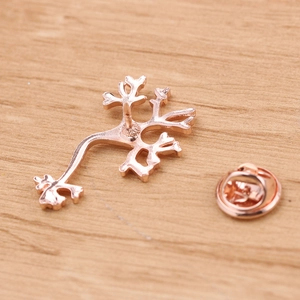 Detail of rose gold anatomical branch brooch with butterfly clutch on wood background