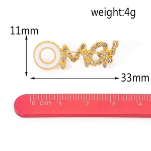 Detail van OMG gouden broche met wit emaille en micro-diamanten op een meetschaal