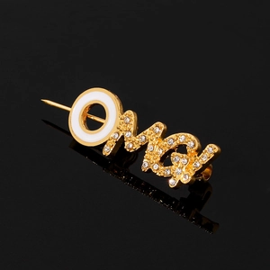 Detailopname van gouden OMG-broche met kristallen en wit email op zwarte spiegeling
