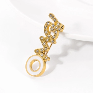 Gedetailleerd beeld van de vergulde LOVE-broche met glinsterende strass en wit emaille