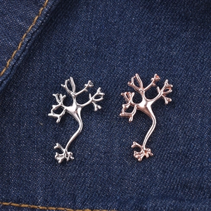 Detail view of neuron-shaped lapel pins in silver and rose gold finishes on denim cloth