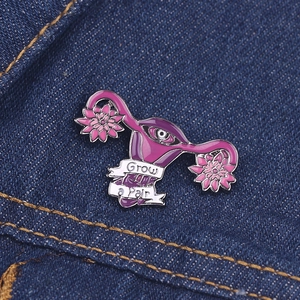 Detail of flower enamel brooch with eye motif and Grow a pair text on denim background