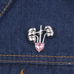Detailed close-up of a silver-toned kidney organ brooch with pink heart-shaped crystal on denim