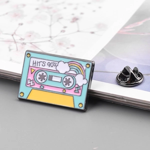 Detailed macro view of a retro 90's cassette enamel pin with a black metal clutch