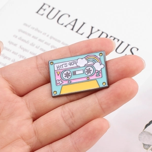 Close-up of a mint green retro 90's hits cassette tape enamel pin with rainbow detail