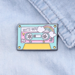 Vintage 90's hits rainbow cassette enamel brooch on blue denim fabric background