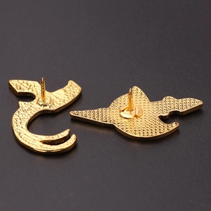Detailansicht der Rückseite goldener Metallnadeln mit strukturierter Oberfläche und Pin