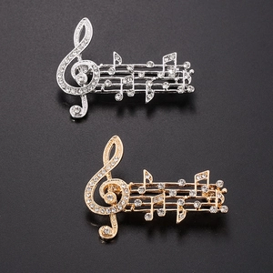 Detailed close-up of musical note brooches in gold and silver finish with sparkling rhinestones