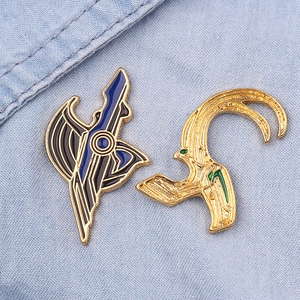 Detailansicht der Loki-Helm-Emaillenadeln und Embleme auf Denim-Stoffhintergrund