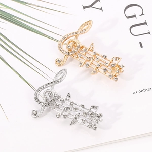 Detailed close-up of musical note brooches in gold and silver finish with sparkling rhinestones