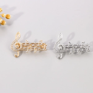 Detailed view of music note brooches with inlaid crystals in gold and silver plating