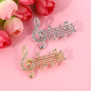 Detailed view of silver and gold musical note brooches with inlaid rhinestones