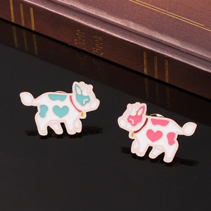Macro shot of blue and pink enamel flying cow pins with heart patterns on a reflective base
