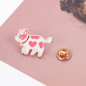 Detailed close-up of a cartoon cow enamel pin with pink heart pattern and gold clasp